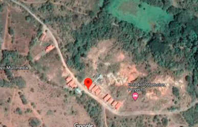 Vacant plot with dry grass, bushes, and trees under clear sky in Blass Tello Chitré Panama