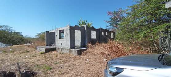 Concrete structure under construction with trees and dry grass on lot Chitré Panama