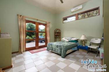 Living room with stone fireplace, sofas, ceiling fan, rustic accents in Boquete home