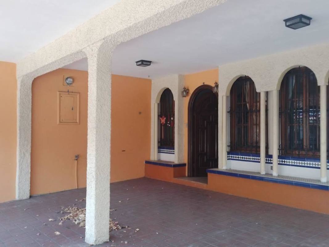 Covered porch with cream stucco walls, arches, wooden door, and decorative tiles at Edison Park Panama