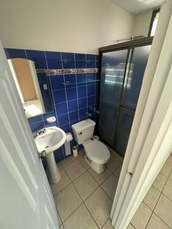 Bathroom with blue ceramic tiles, glass enclosed shower, pedestal sink at PH Park House Panama