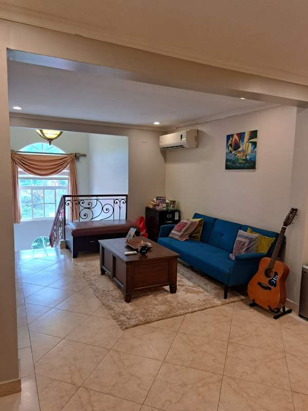 Living room with blue sofa, tiled floor, arched window, AC in Cardenas house Clayton Panama