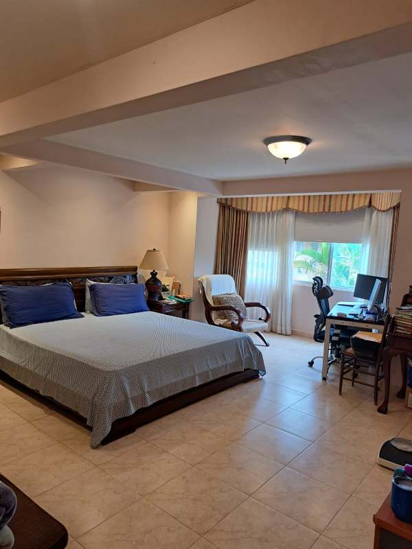 Formal living room with red sofas, piano, large windows in Cardenas Village Clayton Panama