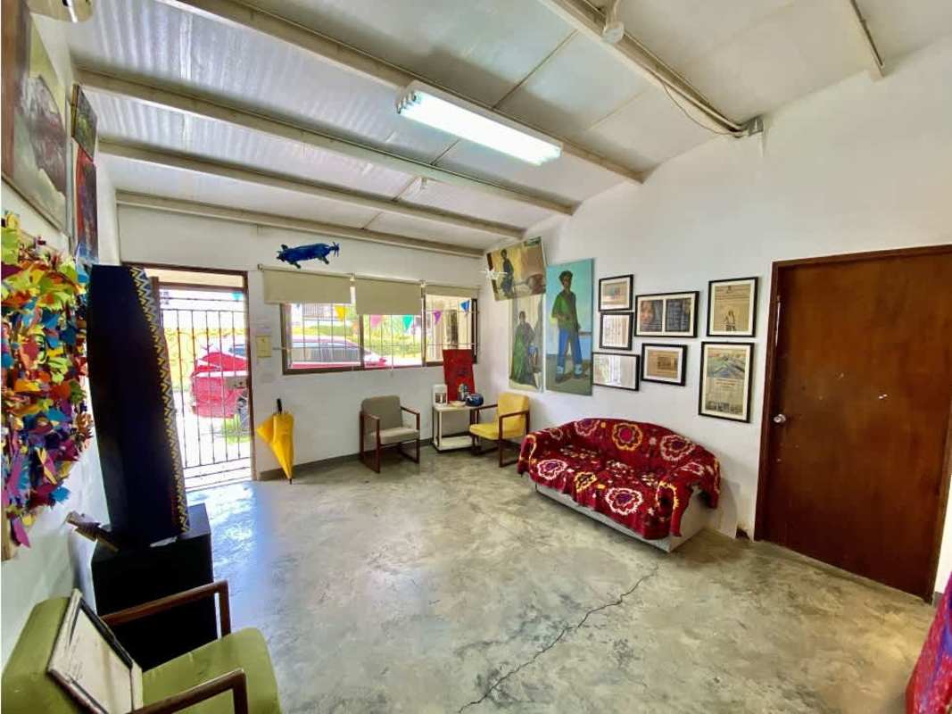 Artistic workspace with paintings, white walls, exposed beams, and furniture in San Francisco Panama