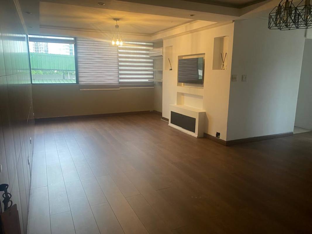 Modern open living room with large window, wood-look flooring, and city skyline view in PH Mirador San Francisco Panama City