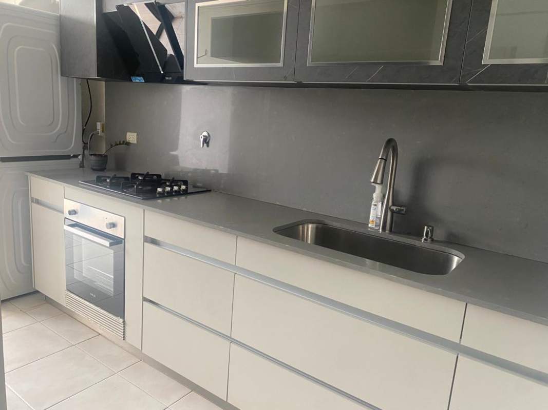 Kitchen space showcasing gas stove, oven, granite countertop and stacked washer/dryer in PH Mirador San Francisco Panama