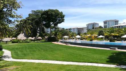 Covered oceanfront balcony with dining and lounge furniture in Bijao