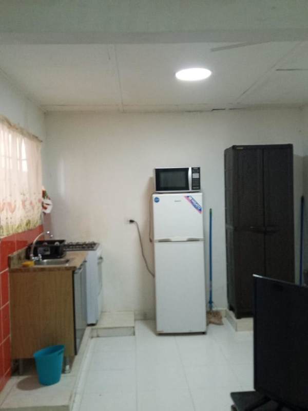 Simple kitchen with stove, refrigerator, plastic storage, microwave in Hato Pintado studio apartment Panama