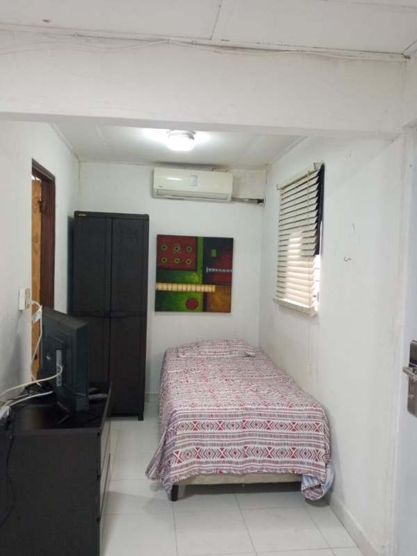 Compact bedroom with AC unit, wardrobe, TV, window with blinds in Hato Pintado studio apartment Panama