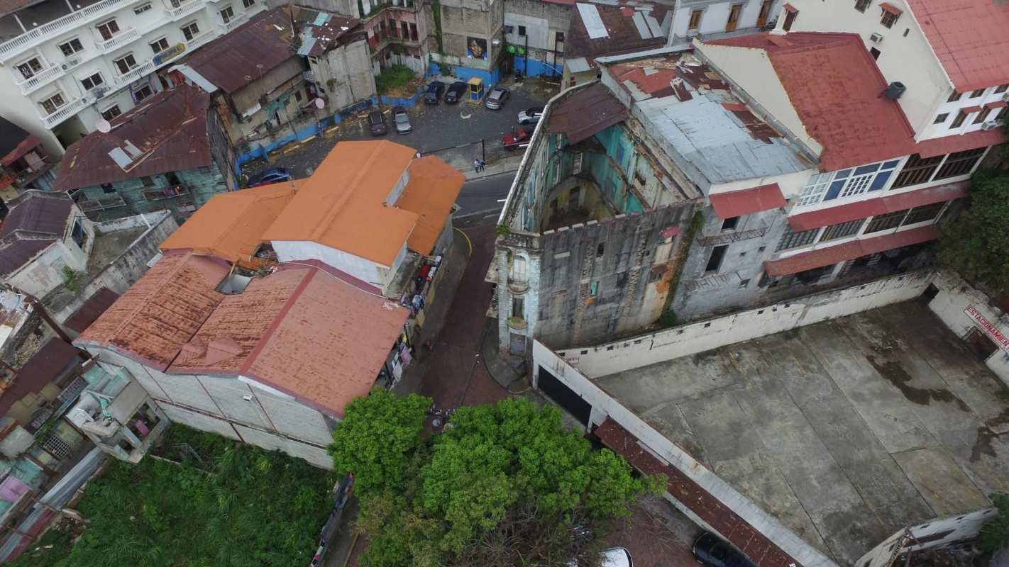 Aerial of colonial buildings with rusted roofs and vacant lot in Casco Viejo Panama City