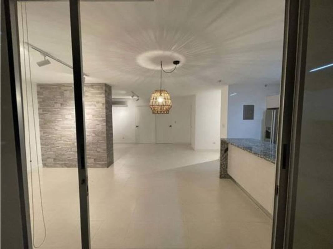 Bright living dining space with stone accent wall, balcony access, tile floor, PH Grey by UNNO Panama City