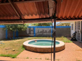 Dining area with green accent wall, bar shelf, eclectic furniture in Chitré Panama