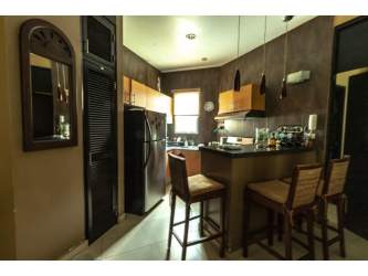 Kitchen with wood cabinetry, breakfast bar, pendant lighting, and appliances in Playa Blanca Panama