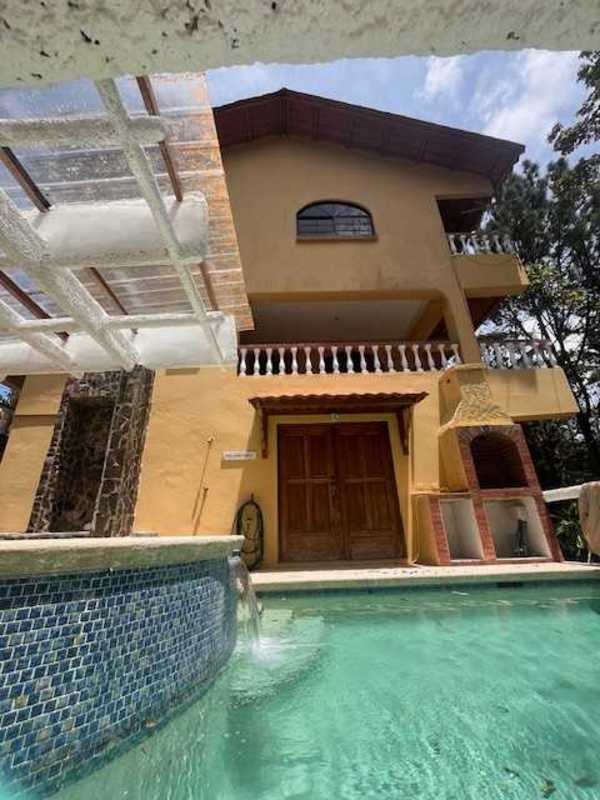 Jacuzzi and swimming pool in rustic patio with pergola, surrounded by lush greenery in Panama mountain community