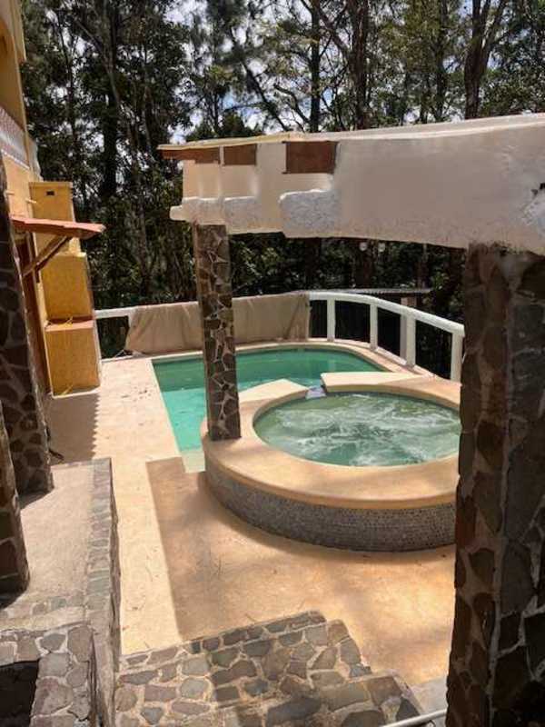 Warm rustic living room with fireplace, leather armchairs, arched windows, and mountain forest view in Cerro Azul