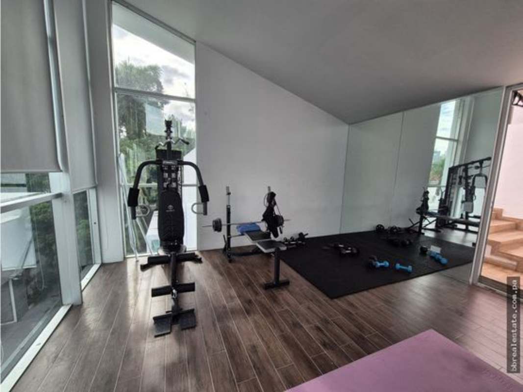 Private fitness room with large windows wood floor equipment minimal house Panama