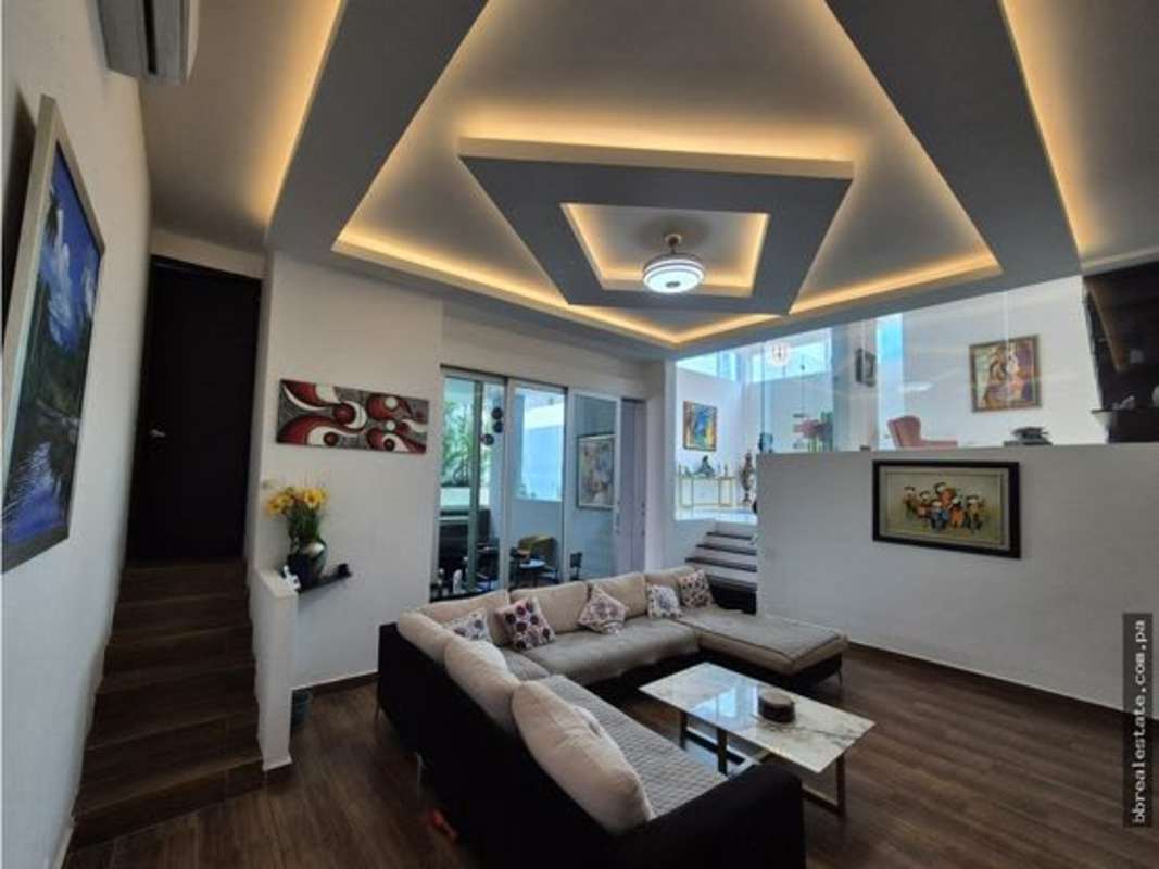 Contemporary living area with L-shaped sofa LED ceiling marble tables minimal house Panama