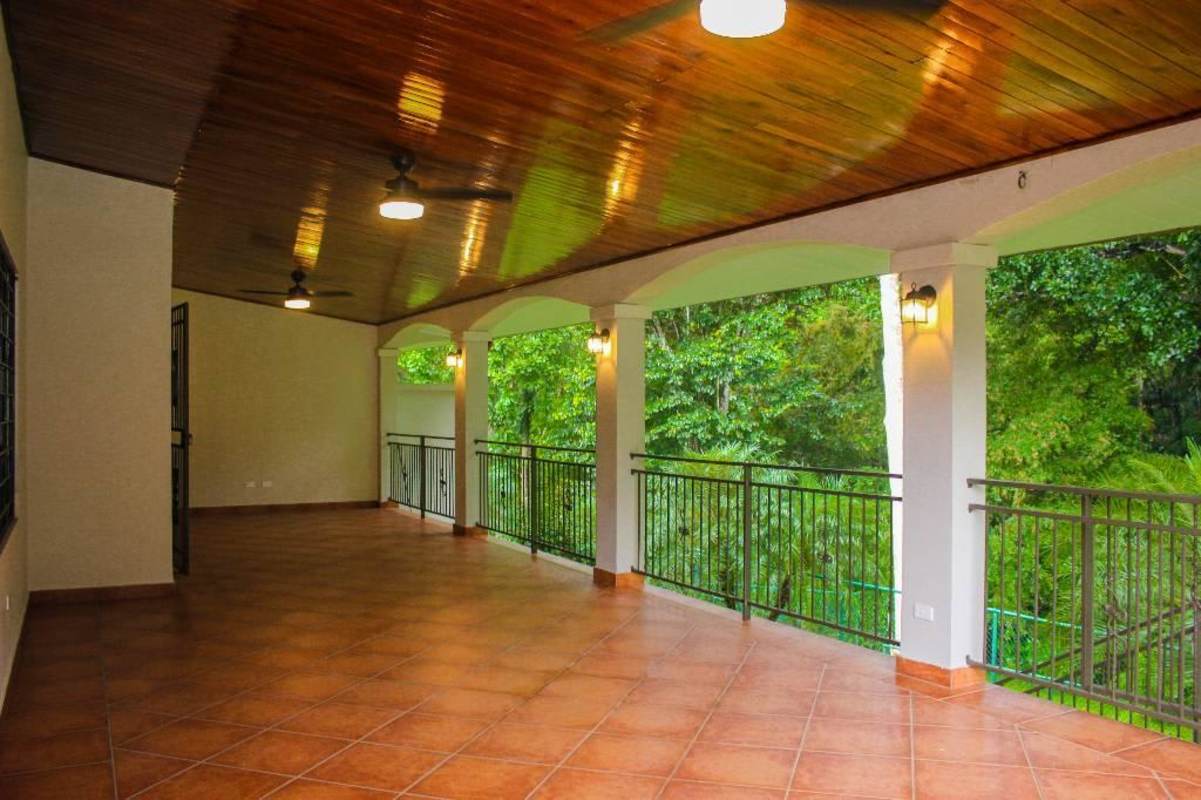 Covered balcony with terracotta floor tiles overlooking tropical garden Cardenas Clayton residence Panama