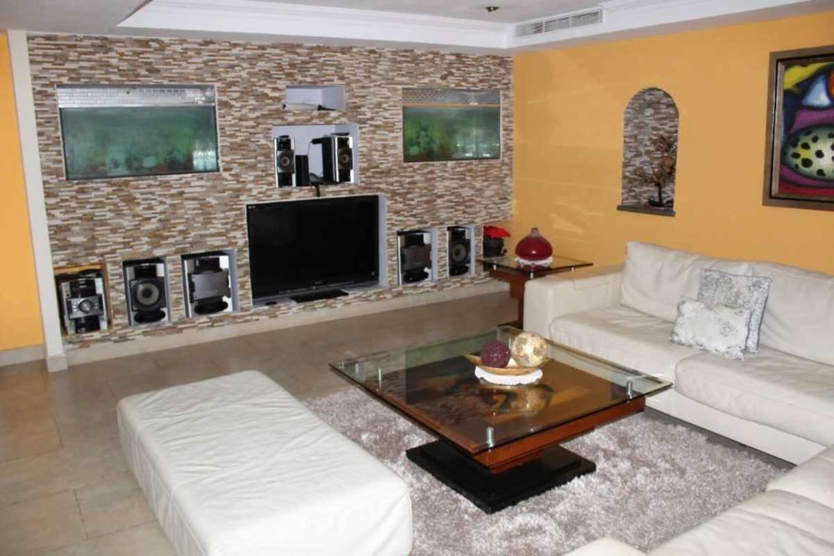 Spacious living room with stone accent wall, flat-screen TV, aquarium and modern sofas in Villa Zaita Panama