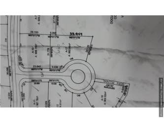 Open grassy plot with red flower and treeline at Hacienda Pacífica San Carlos