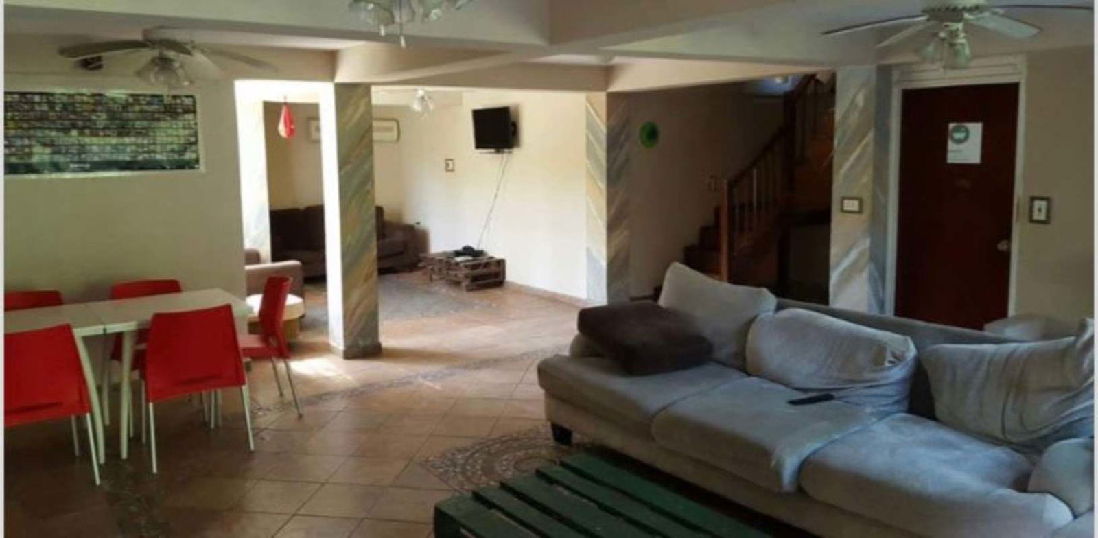 Open living dining area with sectional sofa, red chairs, ceiling fans in Ancon Hill house Panama