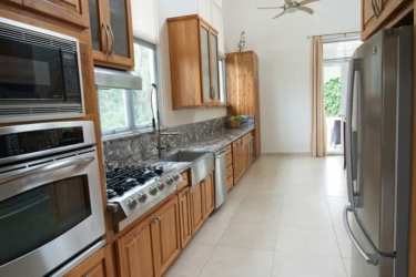 Large gourmet kitchen with granite counters wood cabinetry stainless appliances in Punta Barco Village villa Panama