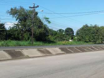 Urban roadside view with concrete drainage and utility poles in vacant land by Divisa entrance Panama