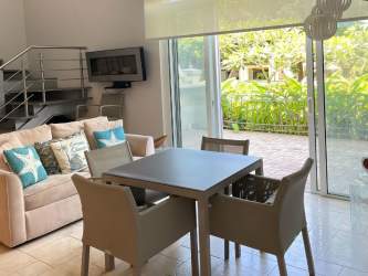 Double-height living/dining area with large windows and balcony in Puntarena beach condo, Buenaventura Panama
