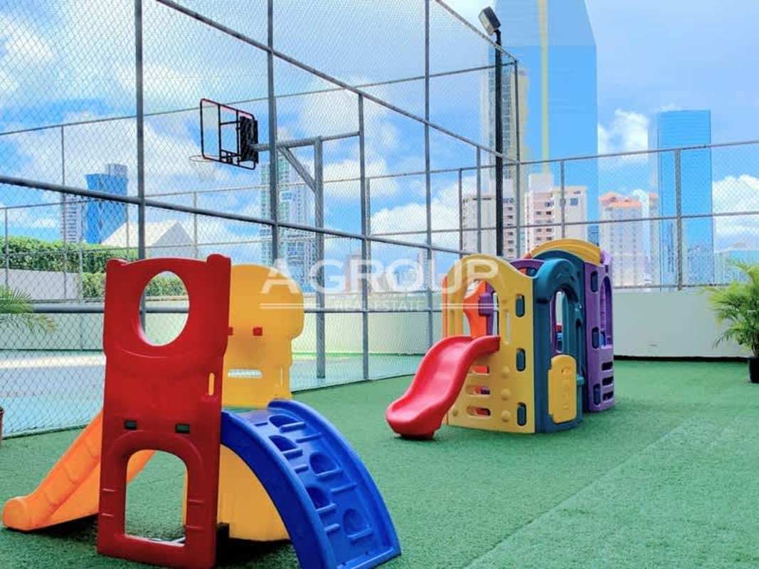 Children's play area on rooftop sports court with skyline backdrop in PH Waters on the Bay Panama City