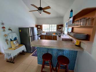 Kitchen with rustic tile counter, open shelves, breakfast bar and appliances in Punta Chame Panama beach house rent