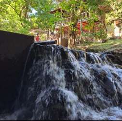 Small waterfall and rustic wood cabin at nature retreat in Panama