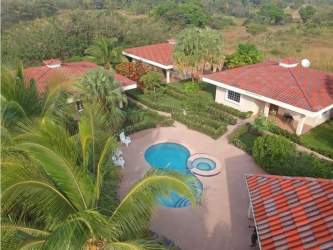 Tropical BBQ social pavilion with red roof, next to swimming pool surrounded by gardens in Santa Clara Panama