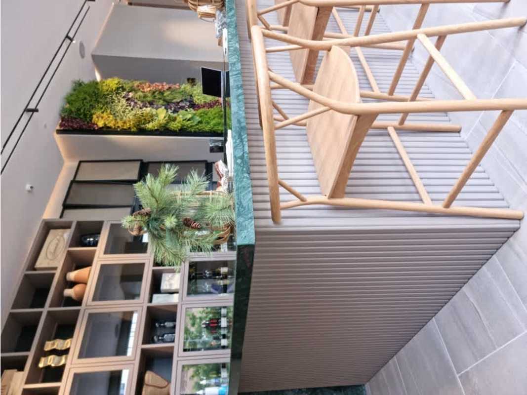 Kitchen bar with marble, wooden stools, green vertical wall PH Ocean House Santa María Panama