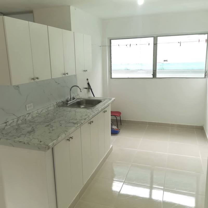 Modern kitchen with marble-style countertop, cabinets and window in La Felicidad complex La Locería Panama