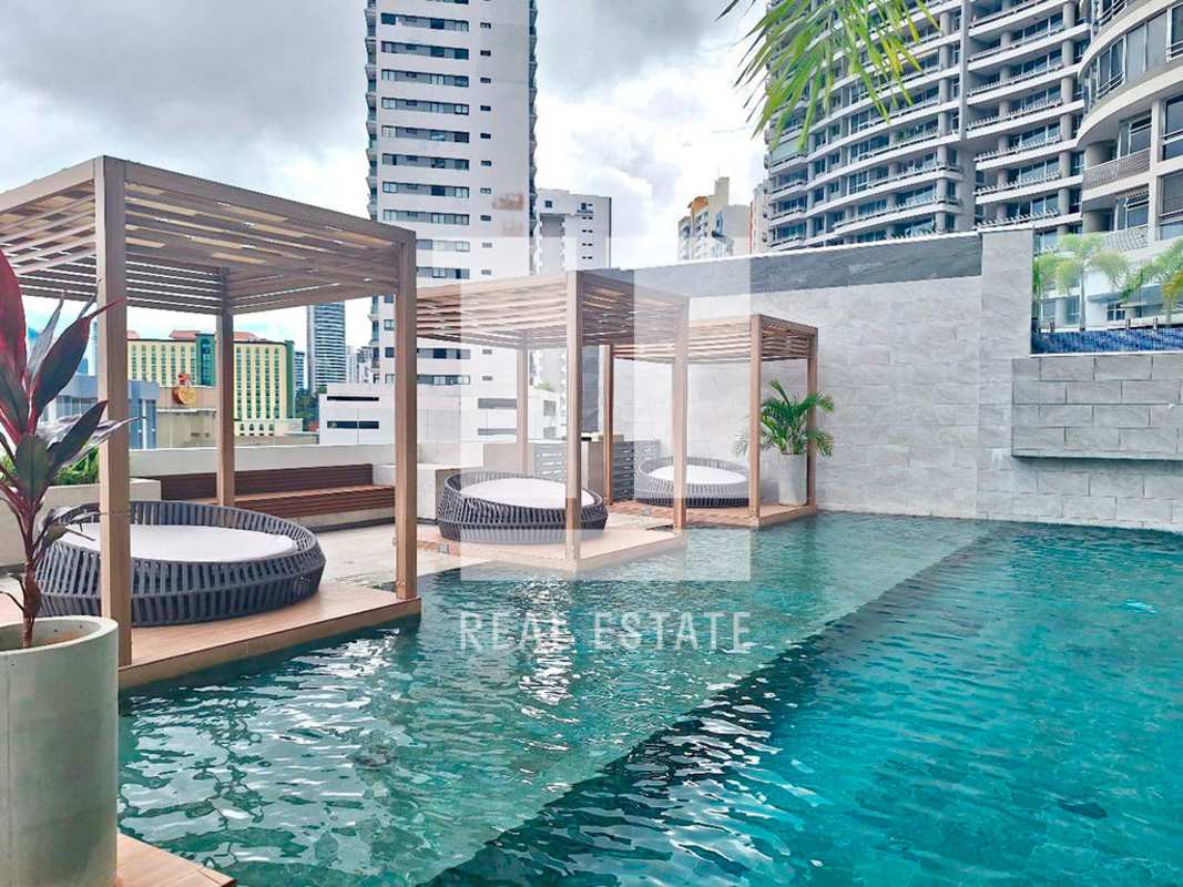 Contemporary pool area with wooden pergolas, deck loungers and skyline view at PH Luxor Towers Panama