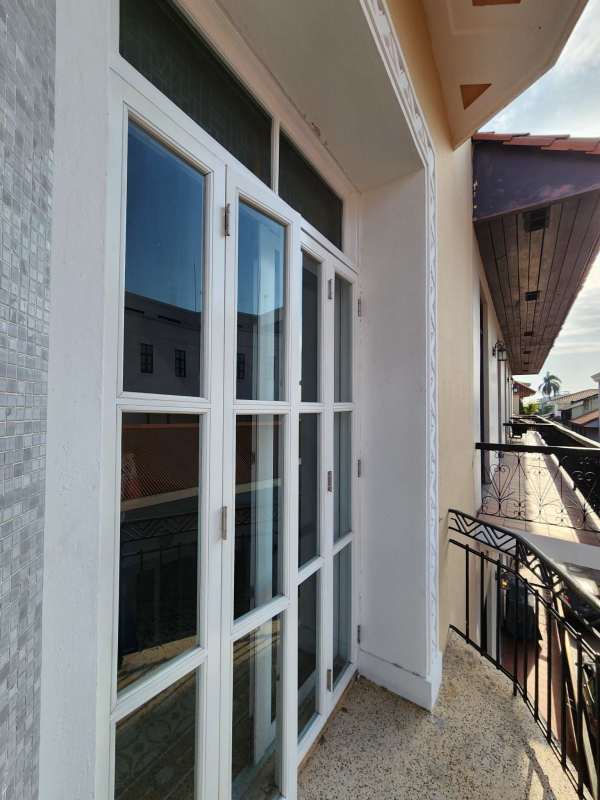 Narrow balcony with French windows, ornate iron railing overlooking Old Quarter Panama City
