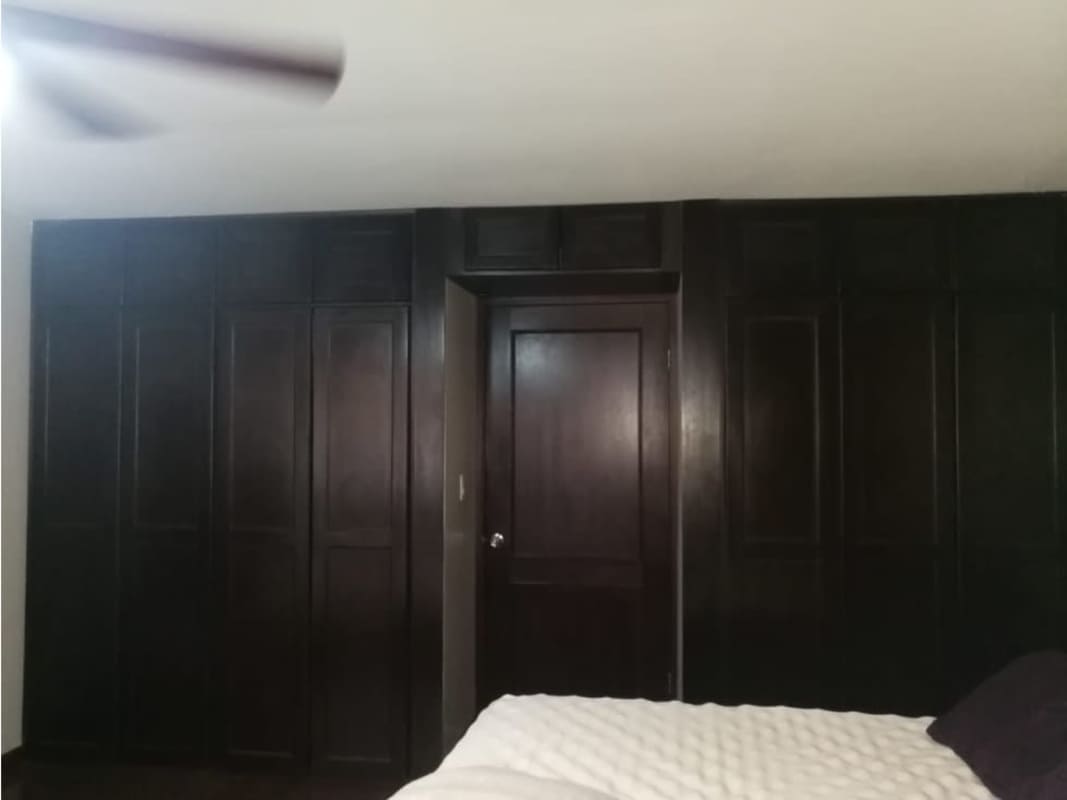 Bedroom with dark wood built-in wardrobe and ceiling fan in Condado del Rey Panama