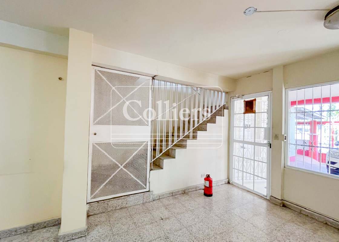 Interior hallway with metal staircase, barred windows, tiled flooring in mixed-use building