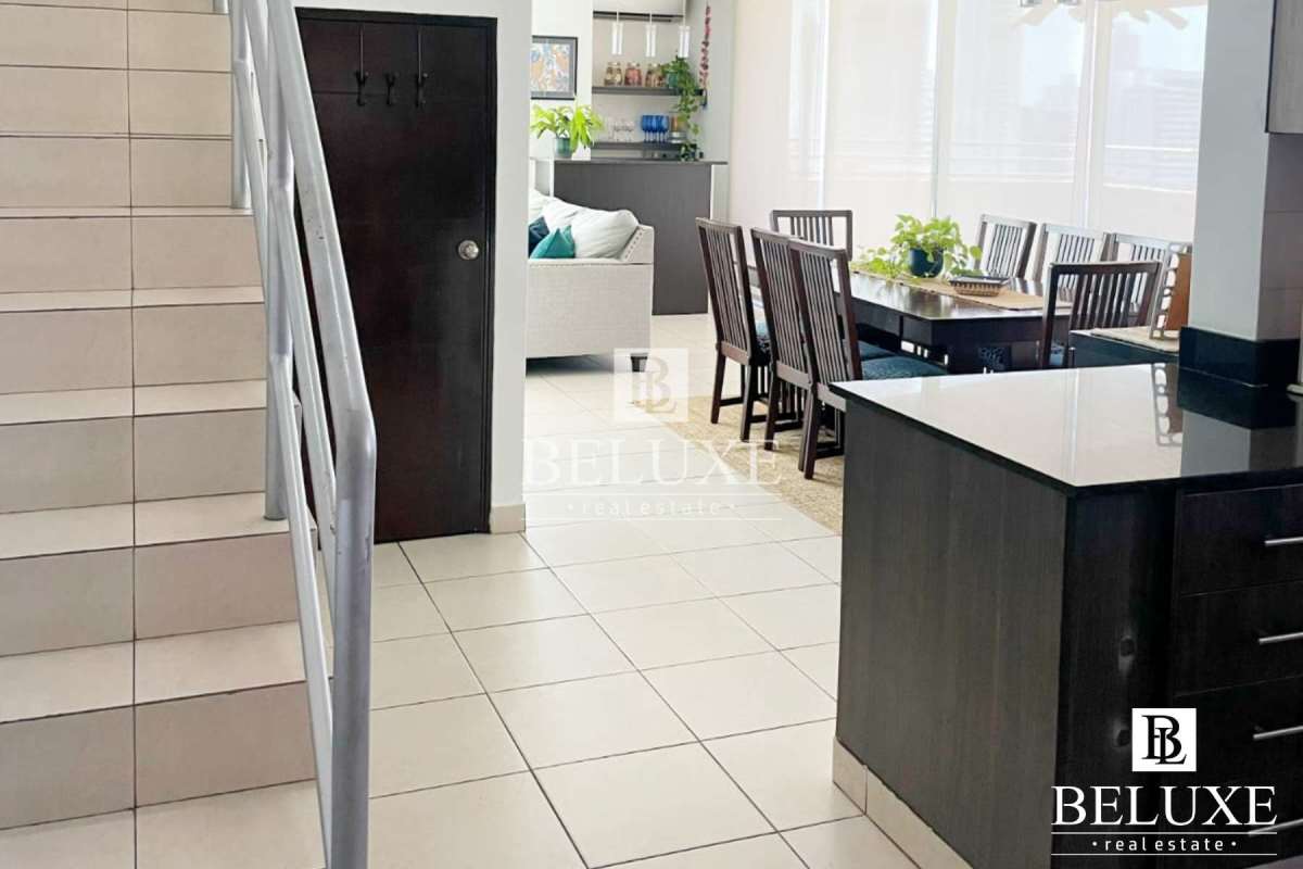 Open-plan contemporary dining and living area with staircase and large windows at PH Concept San Francisco Panama City