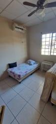 Bedroom featuring AC, ceiling fan, window with metal bars in rental house David Panama