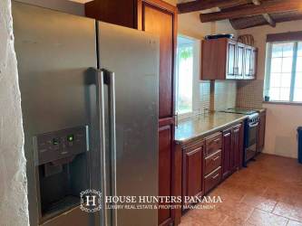 Rustic kitchen with granite countertops, wood cabinetry, stainless appliances at beachfront villa