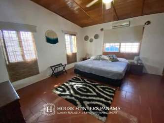 Indoor dining area with large glass doors opening to tropical gardens and Pacific Ocean view