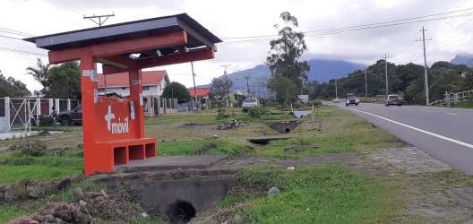 Street view showing front facade of rustic rural house and nearby bus stop shelter in Volcán Chiriquí Panama