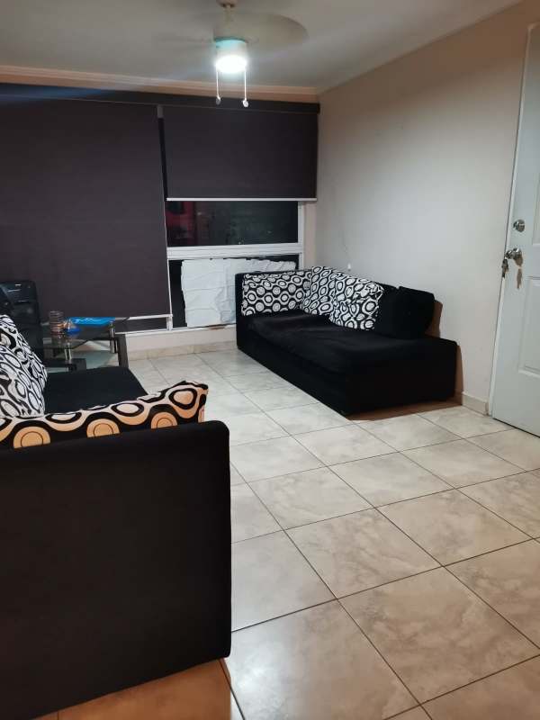 Spacious tiled living room with black sofas and natural lighting PH Girasoles