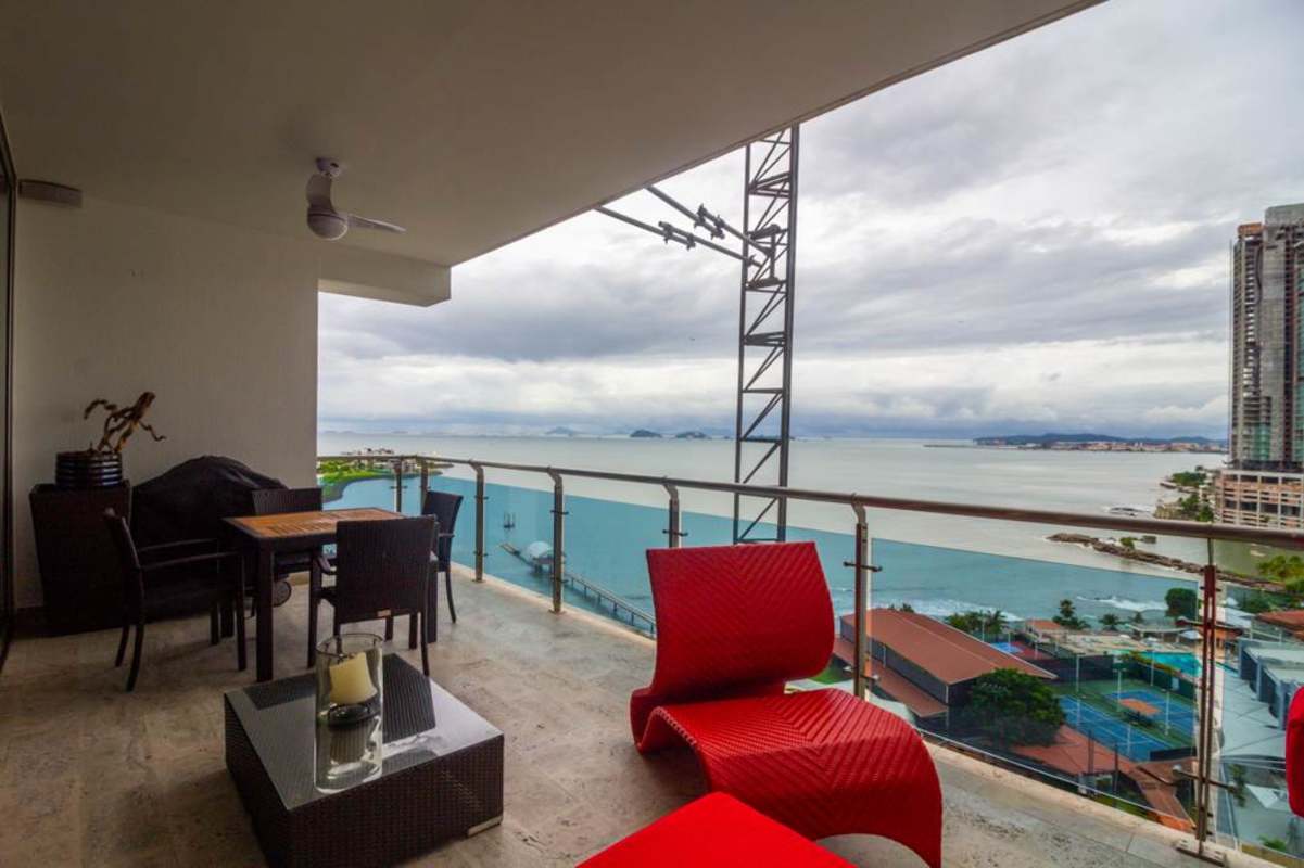 Spacious balcony with panoramic ocean and city skyline views, red modern furniture in PH Aqualina