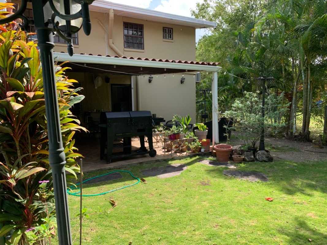 Backyard with covered patio, barbecue, potted plants and garden view in remodeled Clayton home