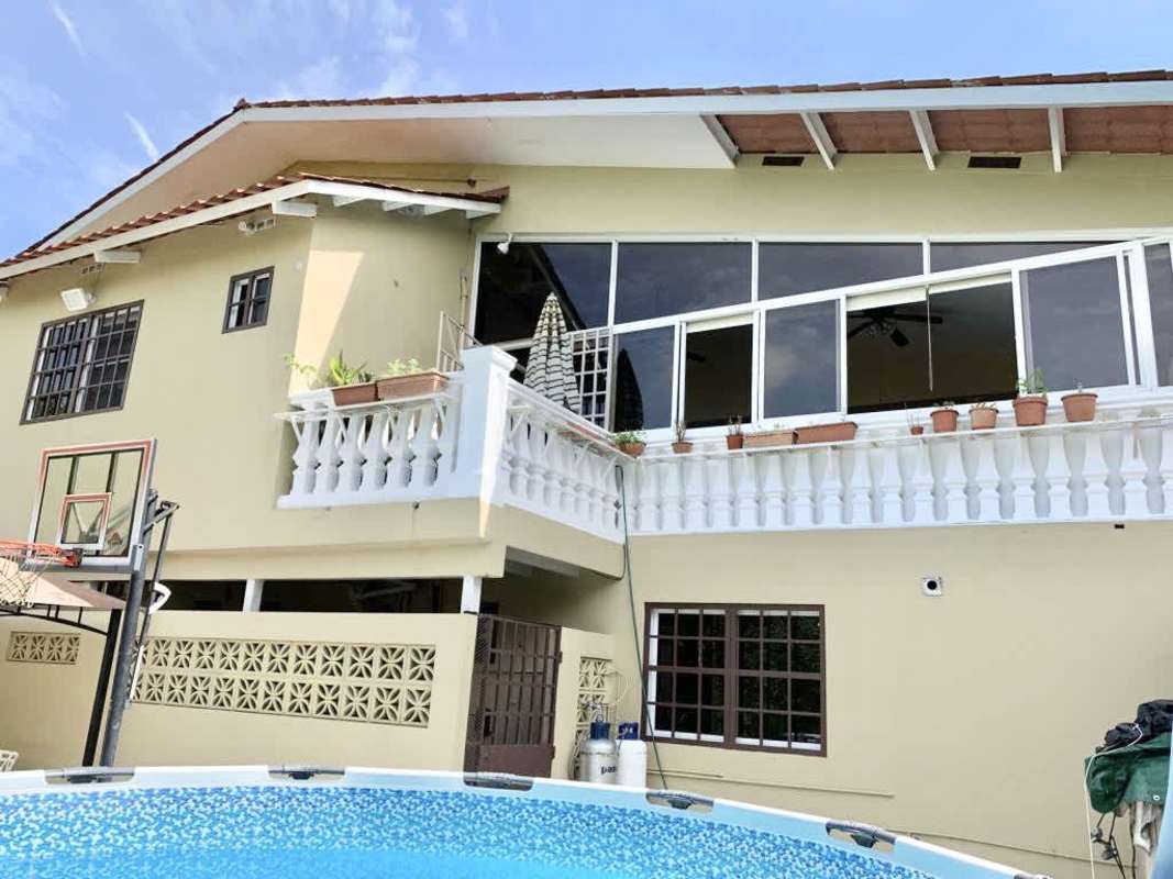 Beige two-story house with balcony, pool, basketball hoop in Clayton neighborhood for sale