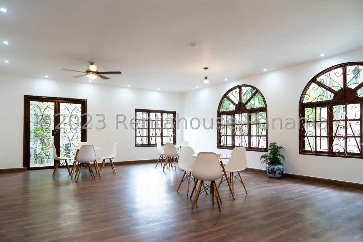 Spacious living and dining space with arched windows, modern furniture, wood floors in Obarrio home Panama City