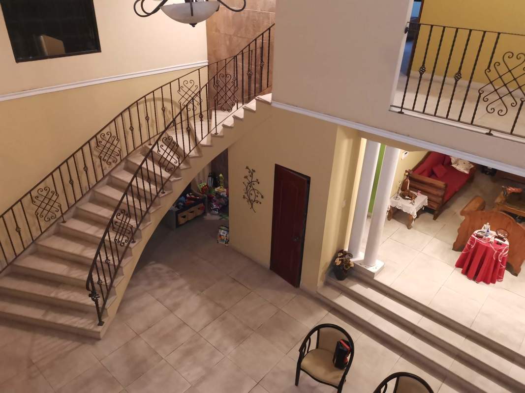 Two-story foyer with curved staircase, tiled floors and grand living area in Mediterranean house Villa Zaita