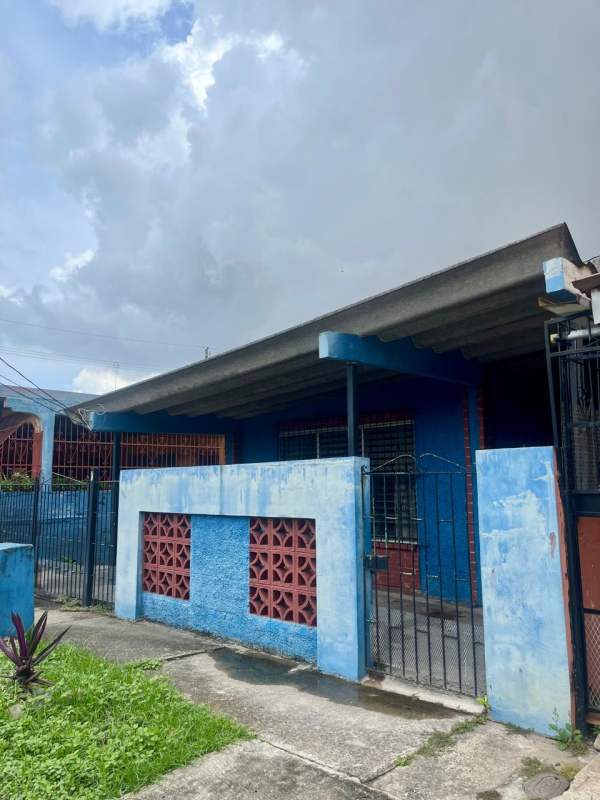 Side of house with garden, security bars, and utility shelves in Villa Venus Panama